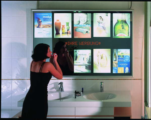 Frau beim Schminken in Sanitaerbereich vor Werbespiegel